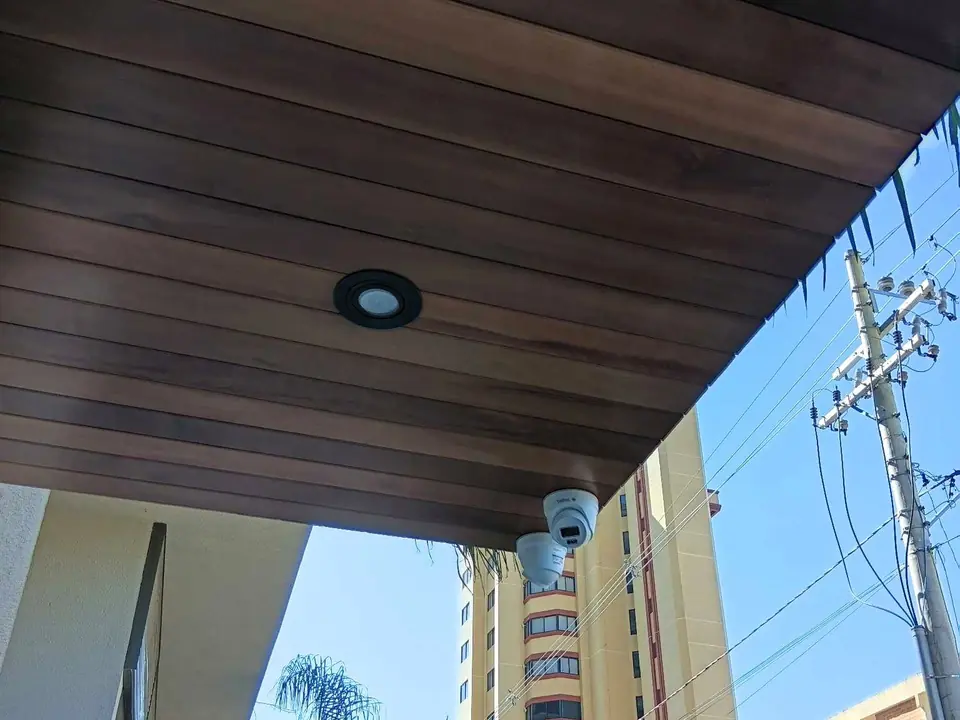 Câmera instalada sob o beiral de madeira de um prédio
