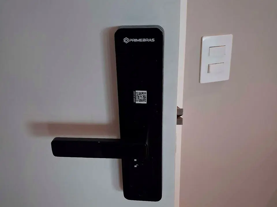 Fechadura digital preta instalada em porta de madeira