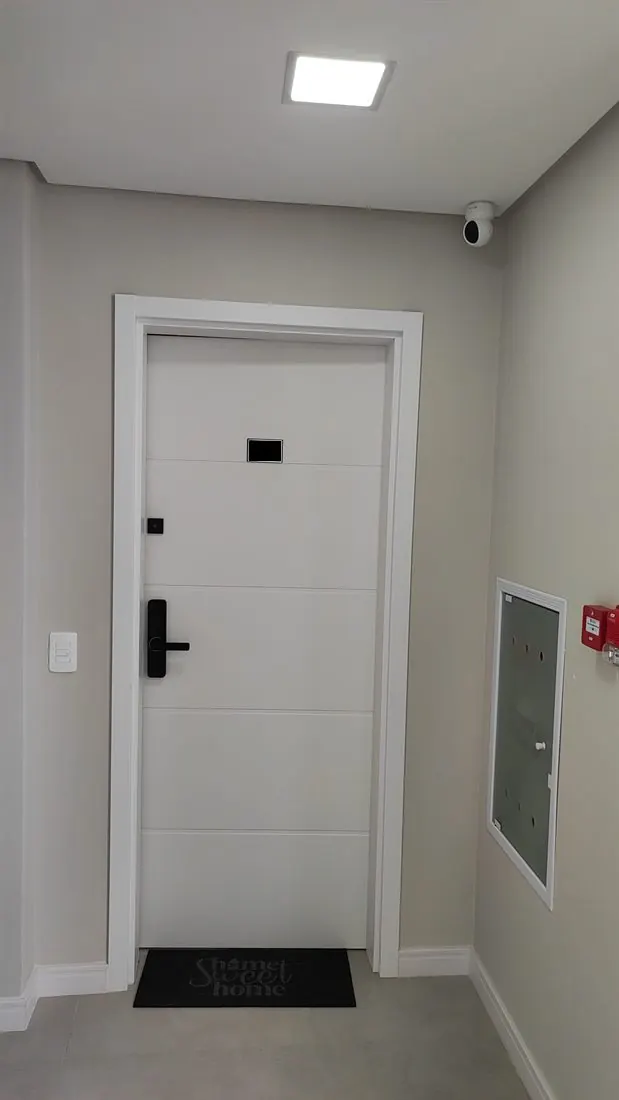 Hall de apartamento com câmera no teto e porta com fechadura digital
