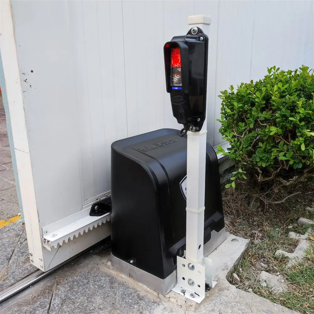 Motor de portão deslizante instalado com semáforo vermelho e verde ao lado do jardim