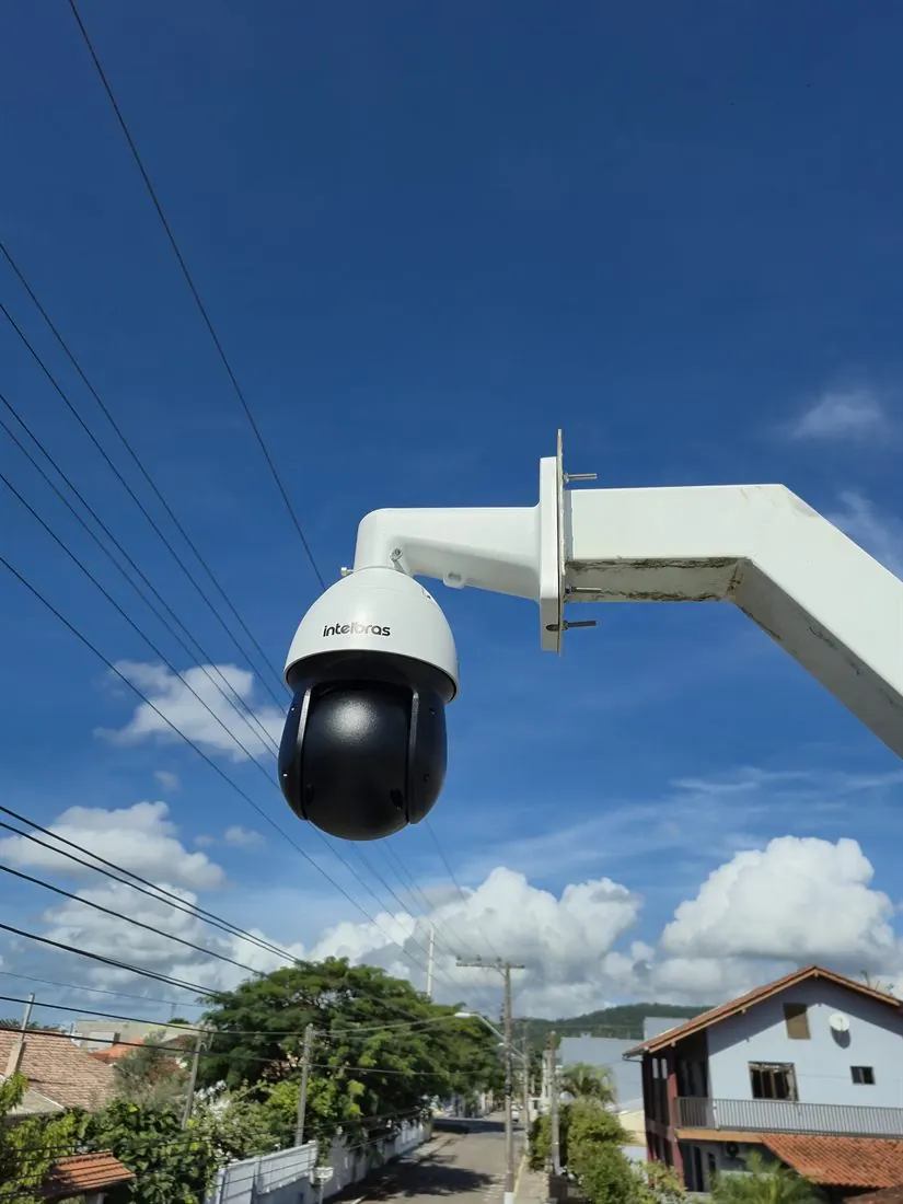 Câmera speed dome Intelbras instalada em braço branco, com céu azul ao fundo
